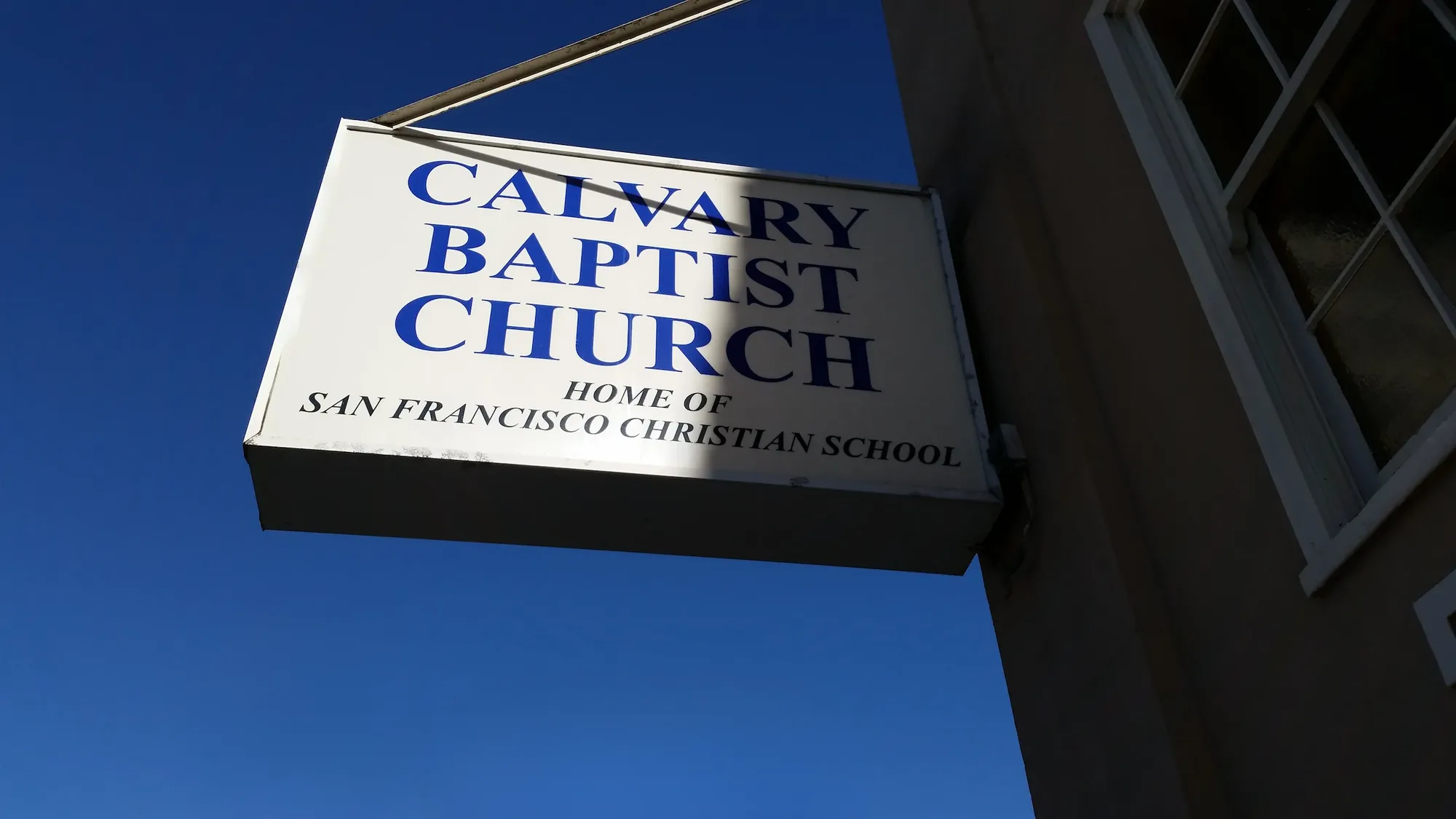 The Calvary Baptist Church blade sign against a blue sky, reading "Home of San Francisco Christian School"