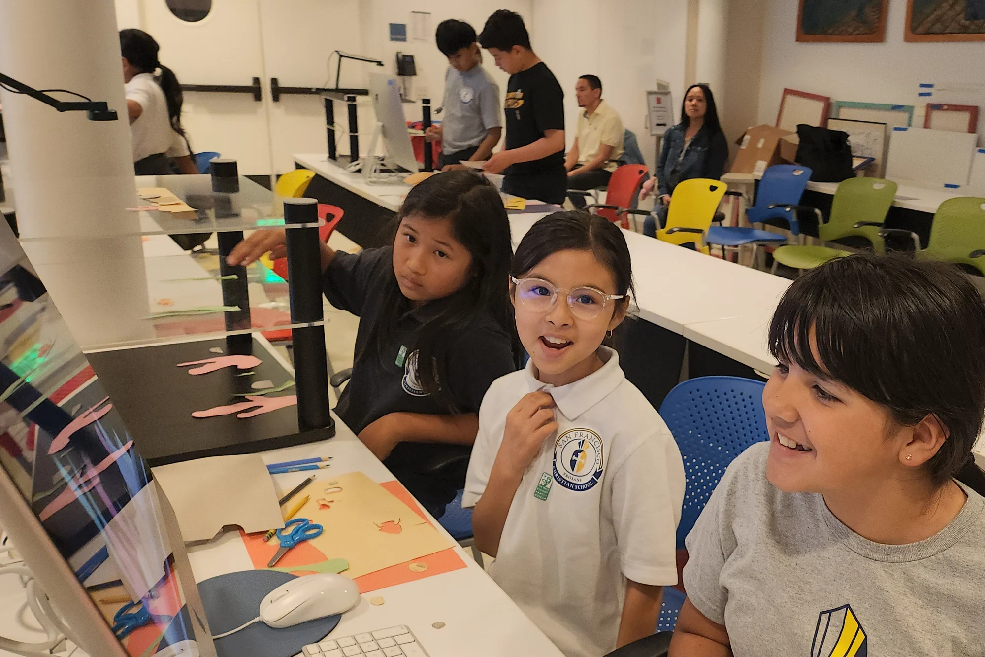 Three students lighting up at the screen during an animation activity on a field trip