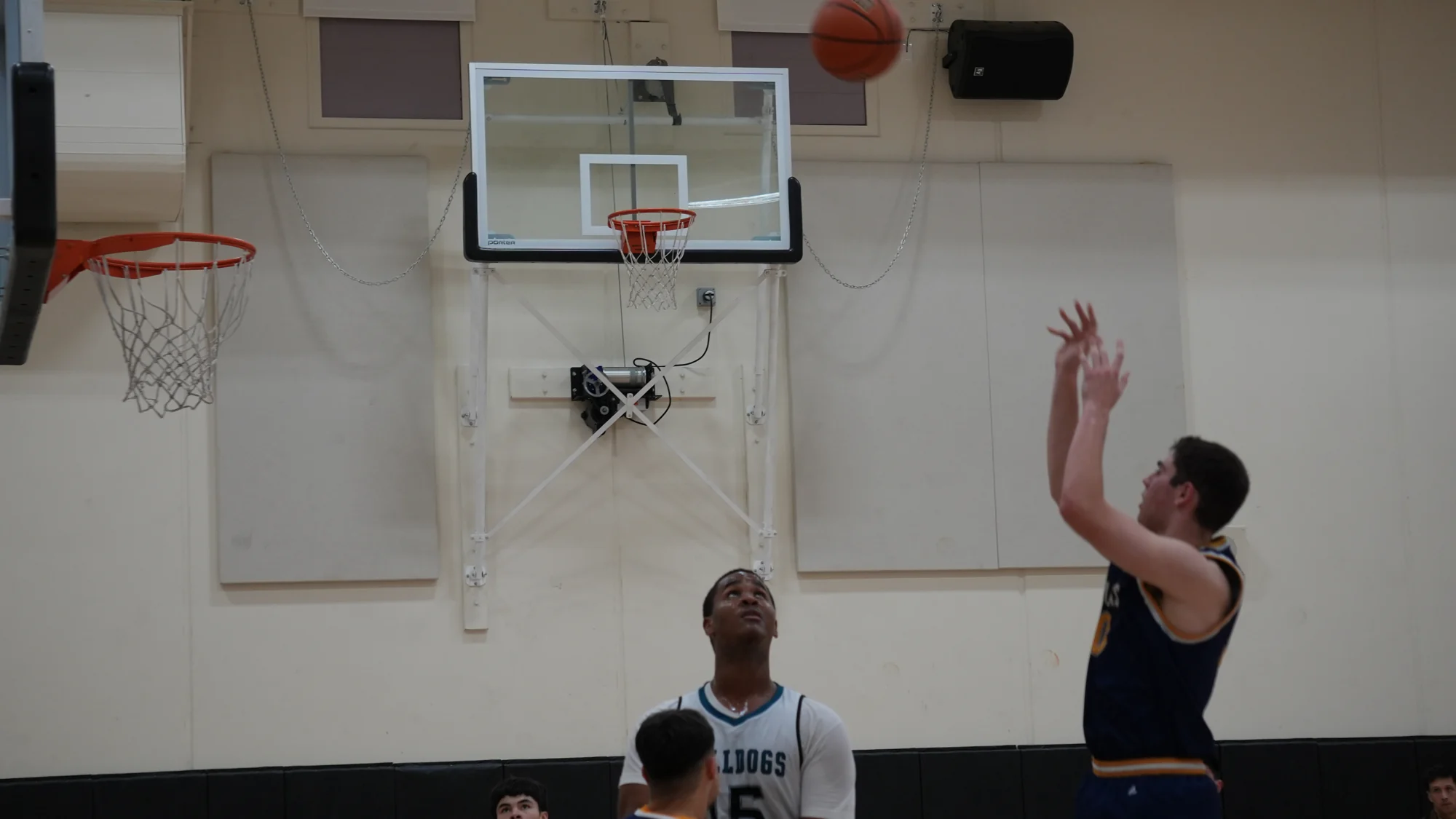 A Trojans basketball player following through on a jump shot with a defender nearby
