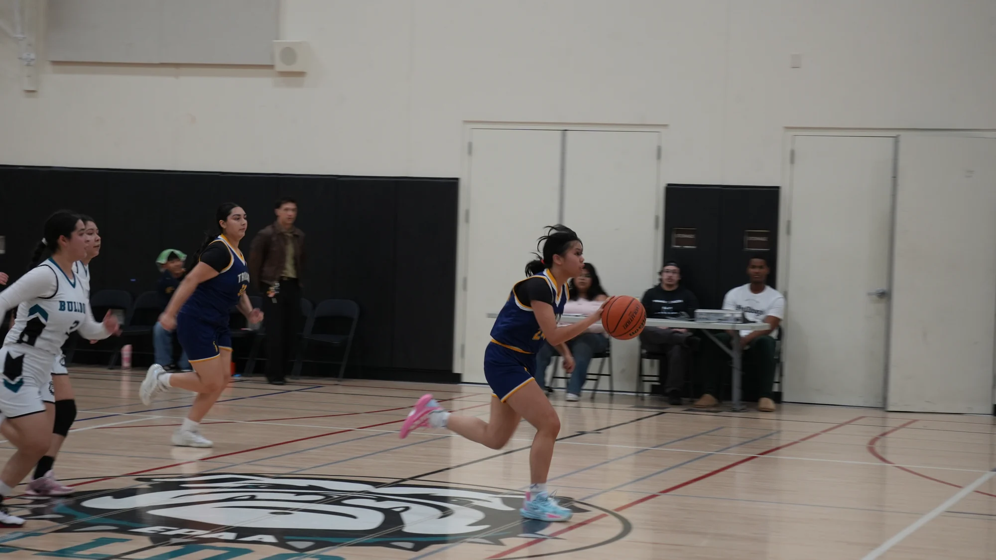 A Trojans basketball player driving toward the basket as teammates follow