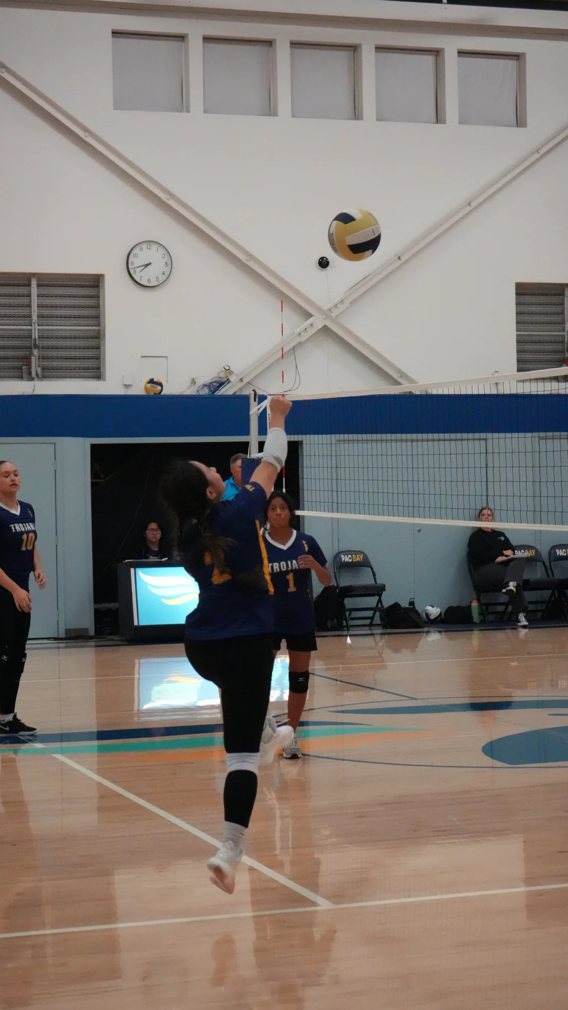 A Trojans volleyball player jumping to send the ball over the net