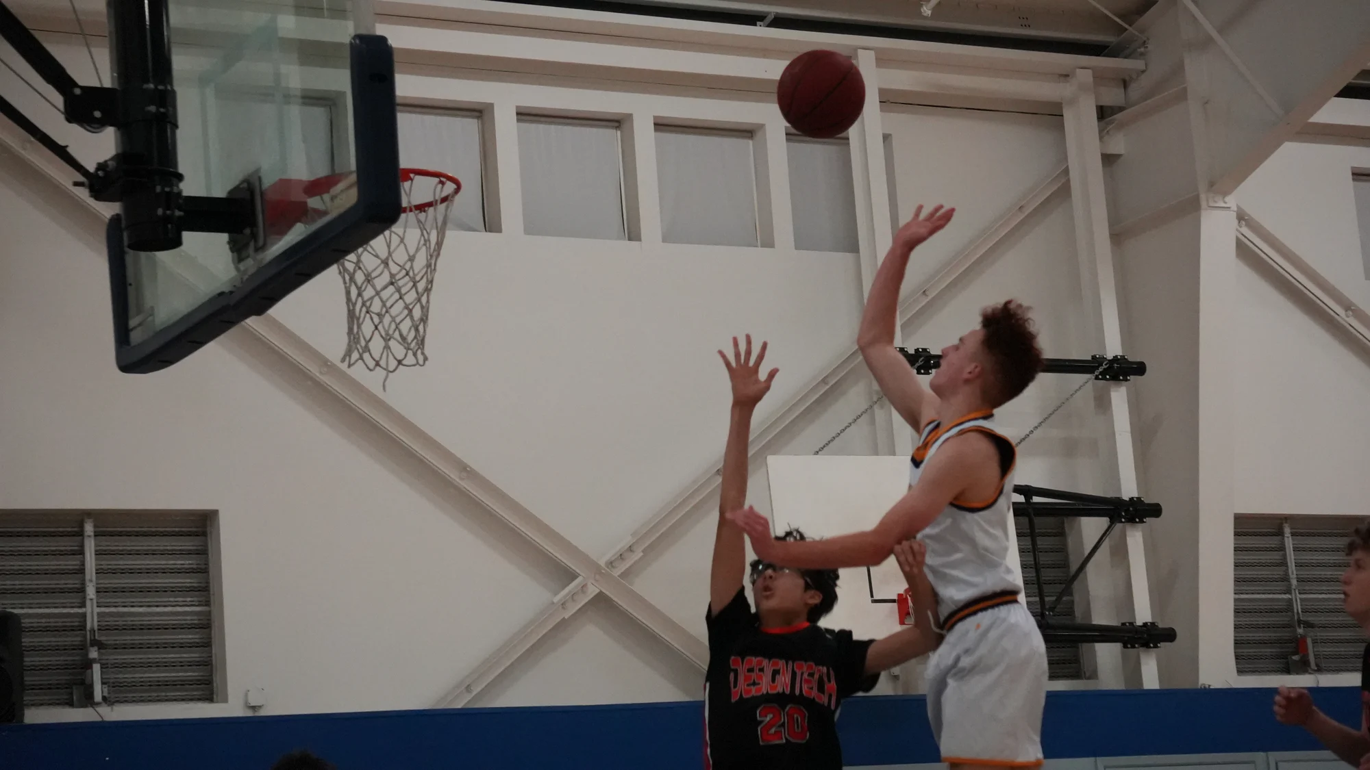 A Trojans basketball player reaching for a layup as a defender contests the shot
