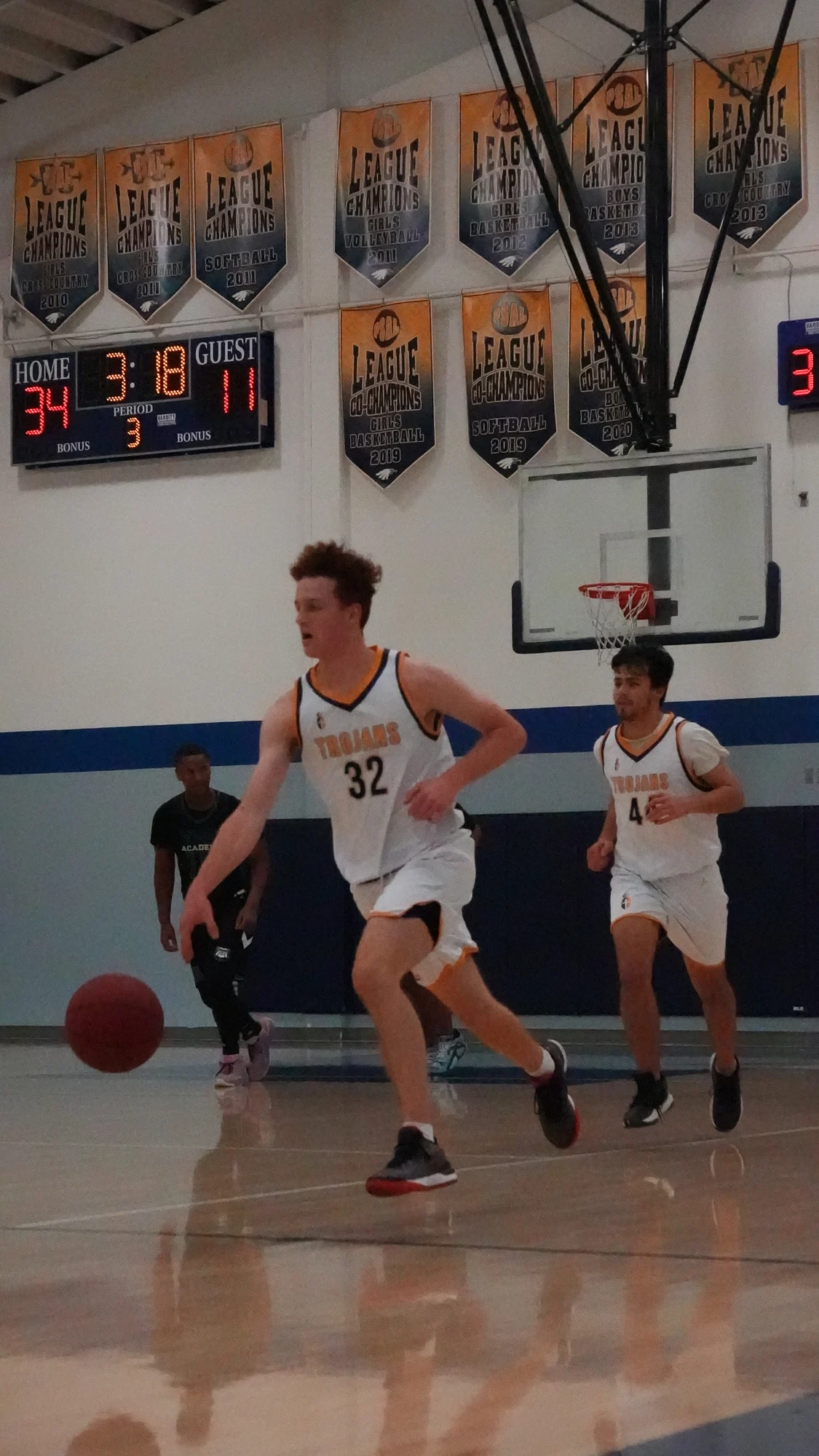 Two Trojans basketball players moving up the court in white jerseys