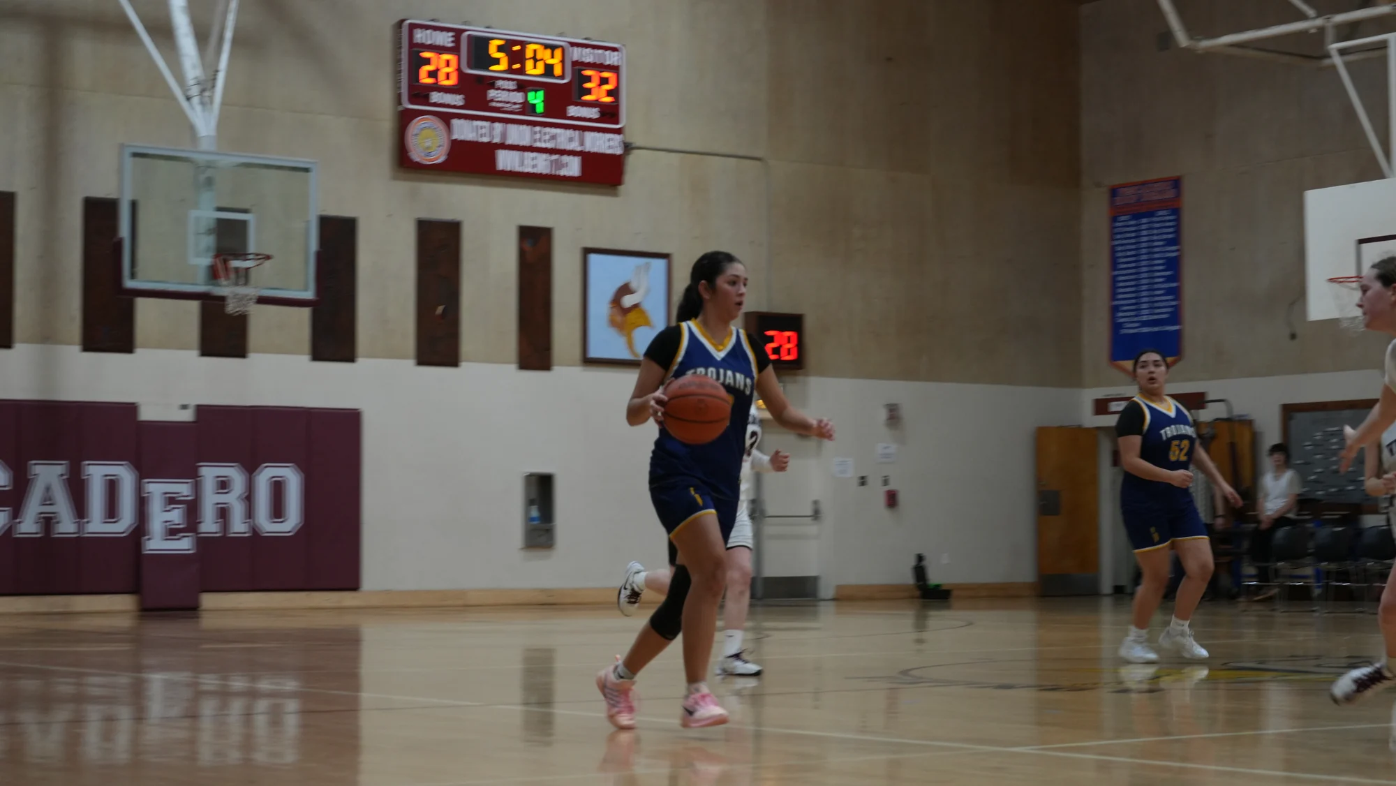 A Trojans basketball player carrying the ball up the court as a teammate follows