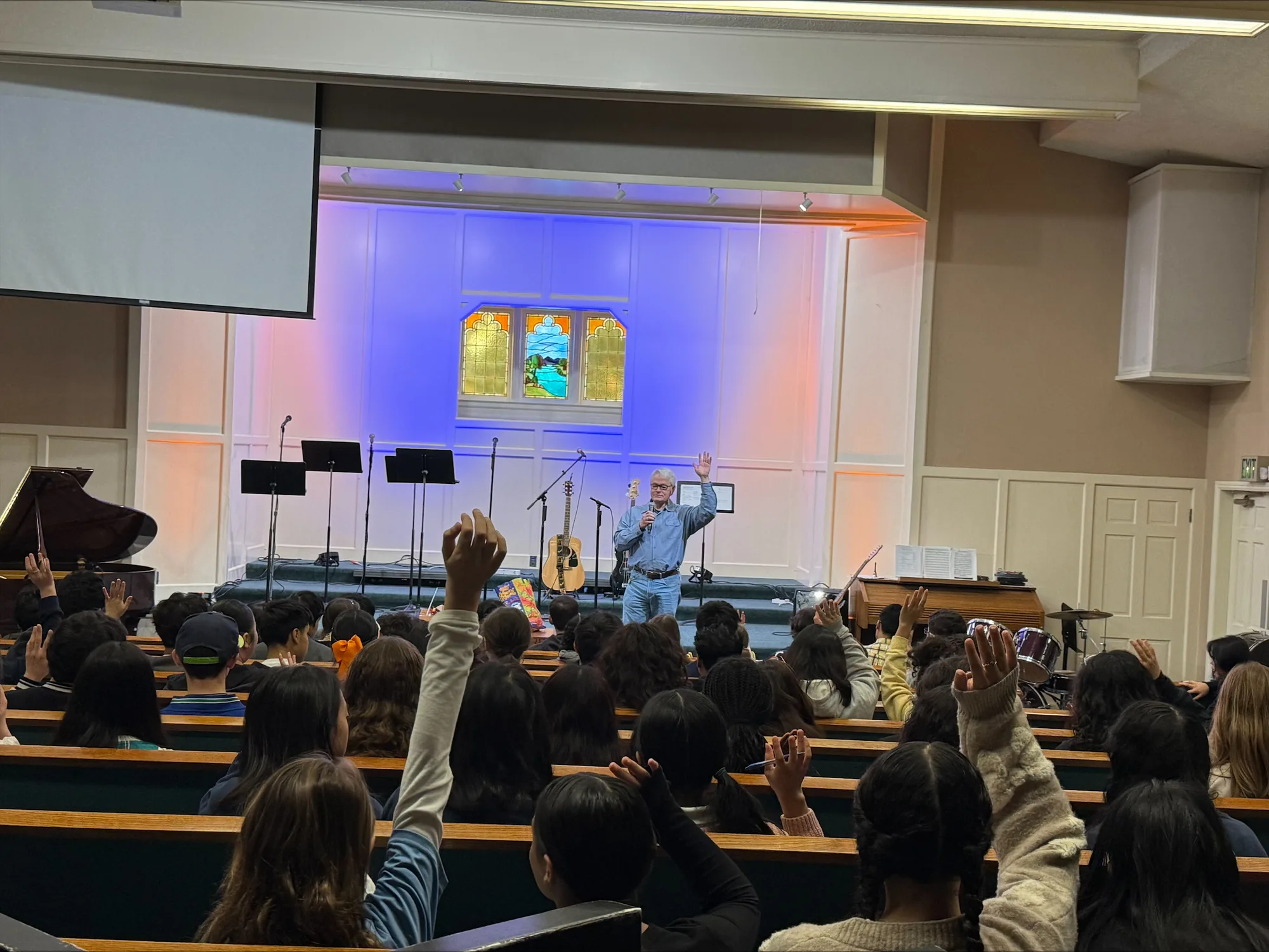 Students with hands raised during a chapel message