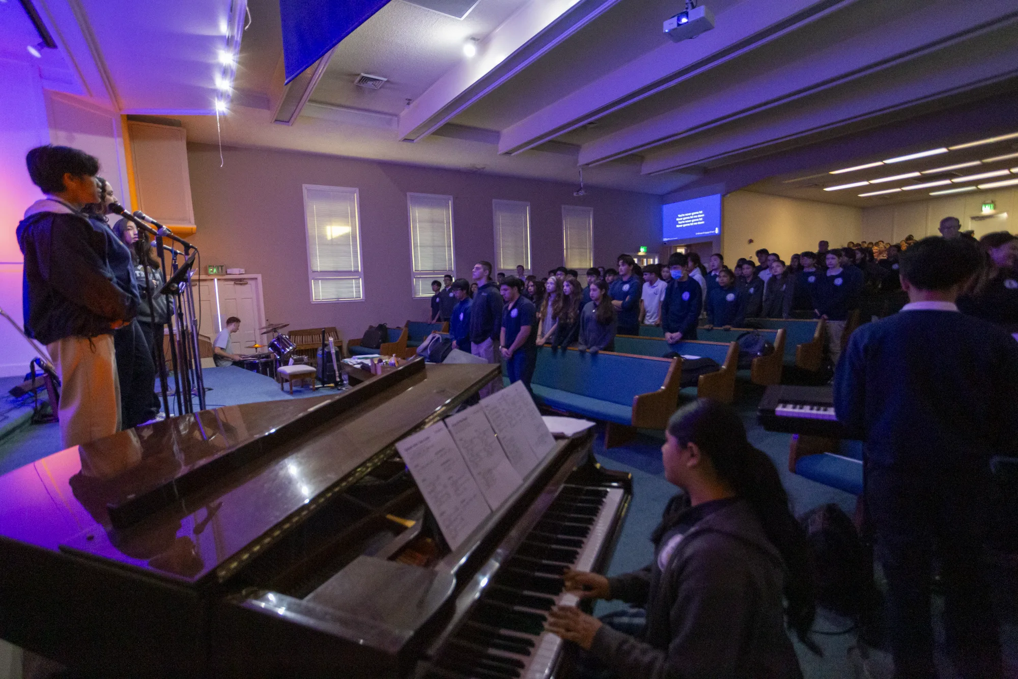 The whole student body in worship during chapel with the piano in view