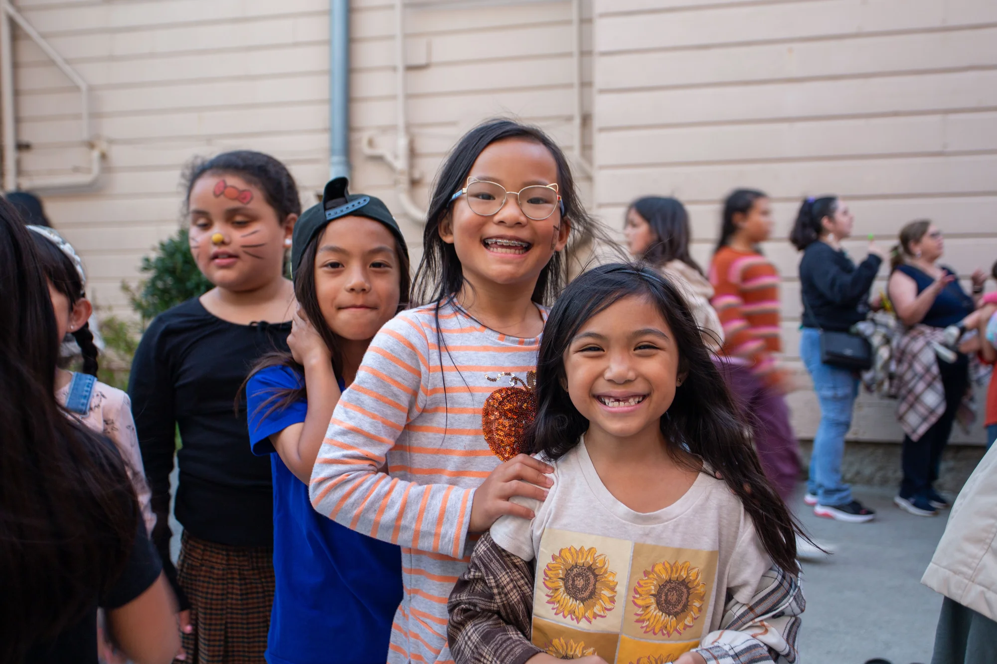 Smiling students, some with face paint, lined up together at the Fall Festival