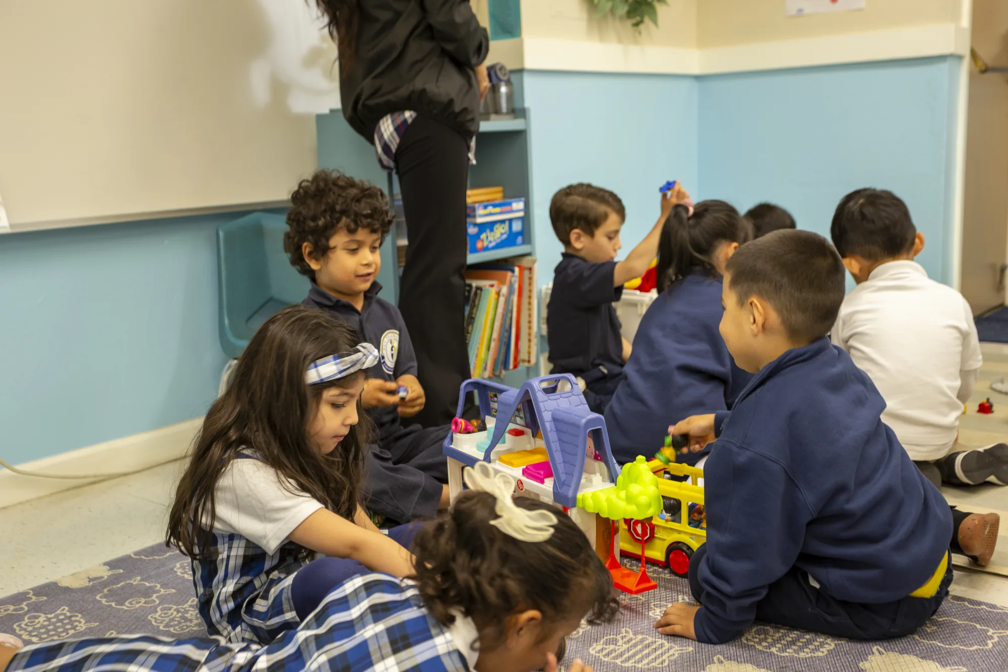 Kindergartners playing on the floor with a toy fire truck and blocks
