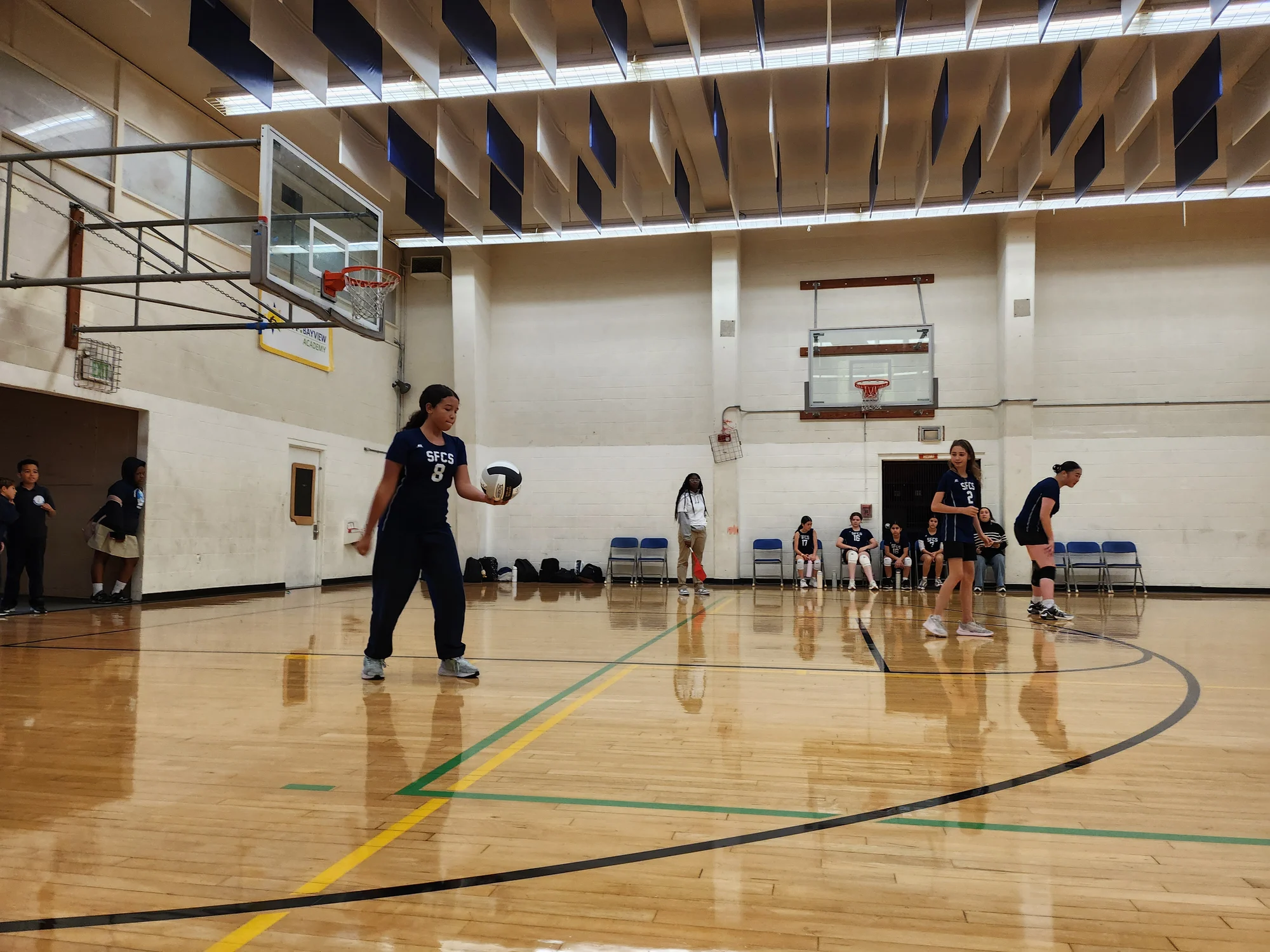 A middle school volleyball player holding the ball before a serve