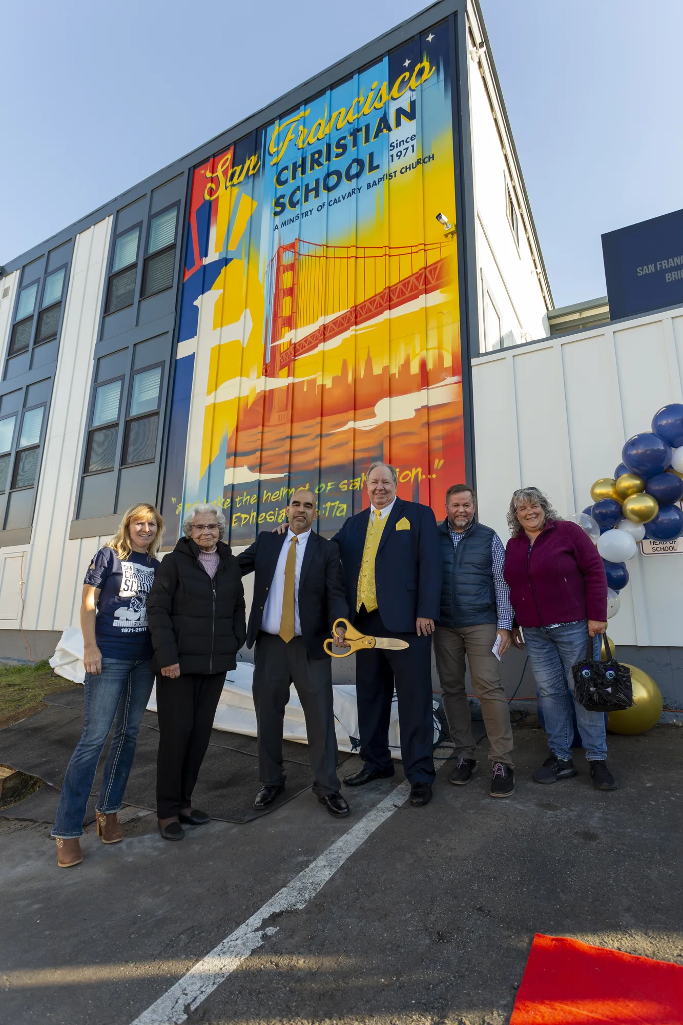 Leadership and founders in front of the revealed Golden Gate school mural with Ephesians 6:17