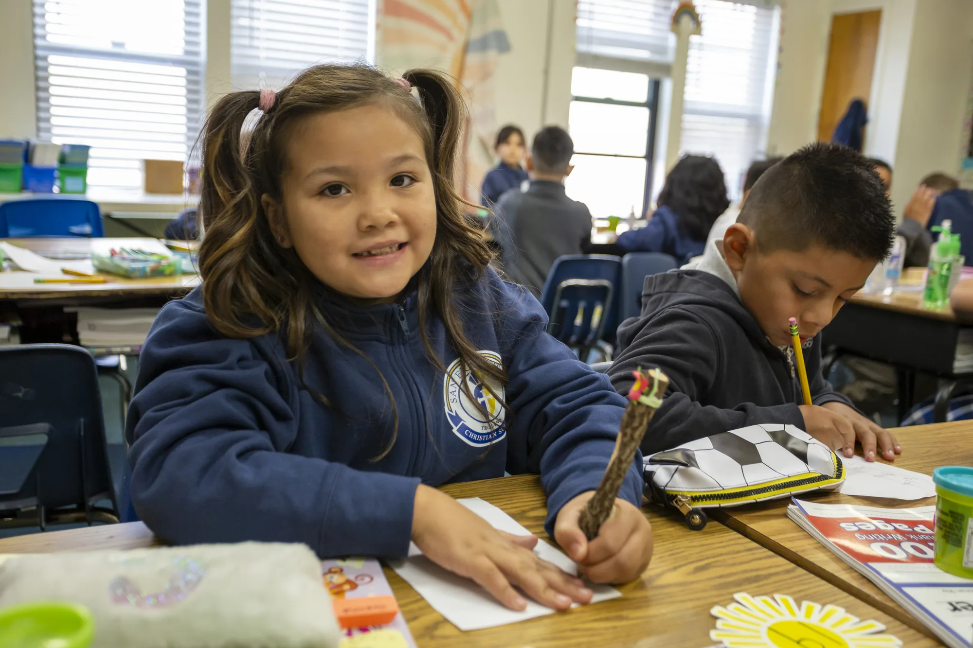 Second graders smiling at their classroom desks