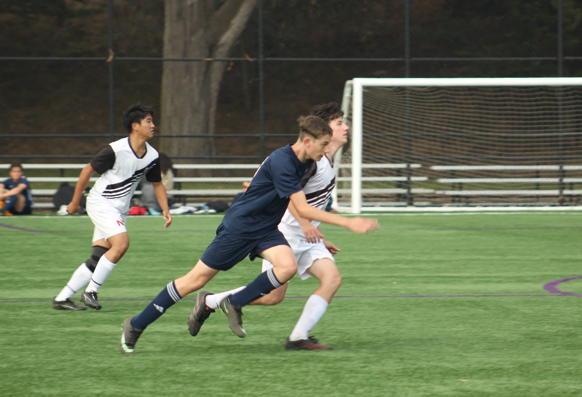 A Trojans soccer player sprinting between two opponents toward the goal
