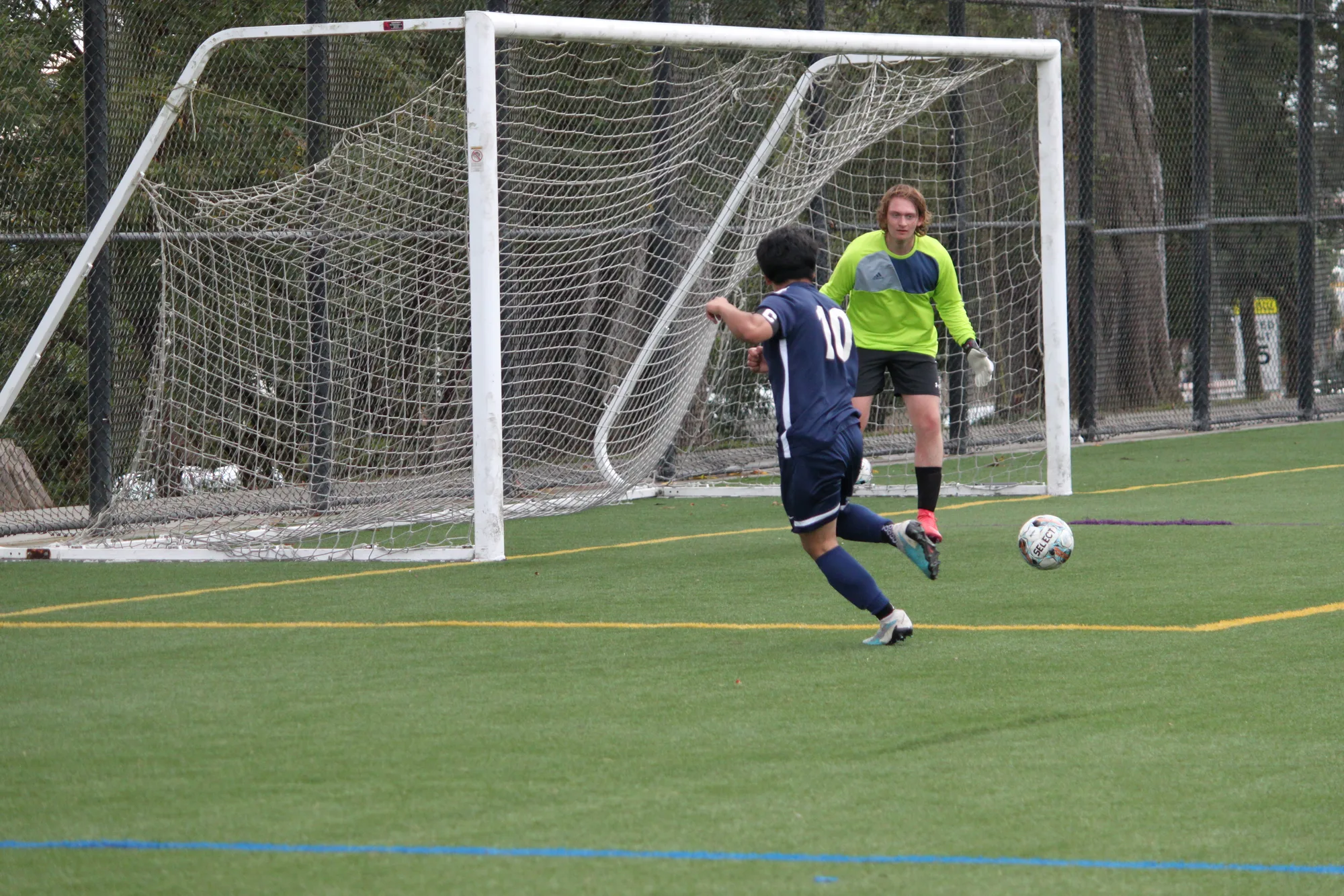 A player shooting past the keeper as a defender closes in