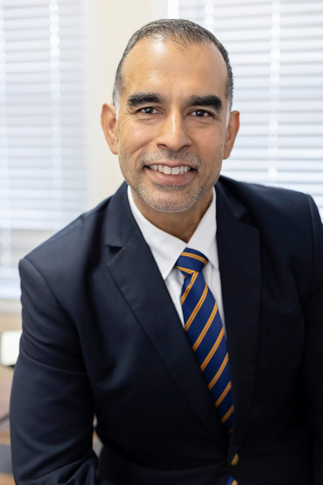 Orlando Duarte, Head of School, in a navy suit and blue and gold striped tie