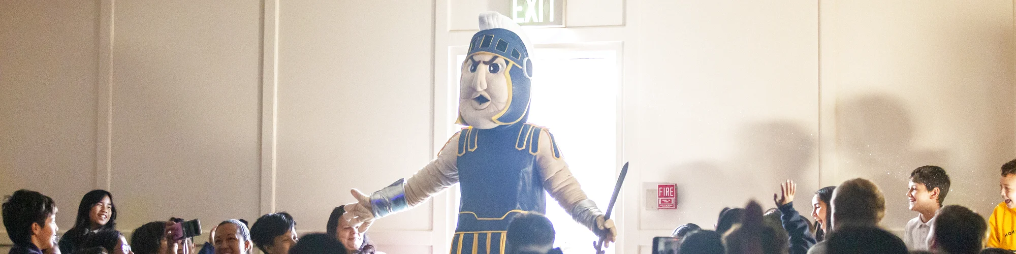 Troy walking into chapel with one arm outstretched as students smile, cheer and film him