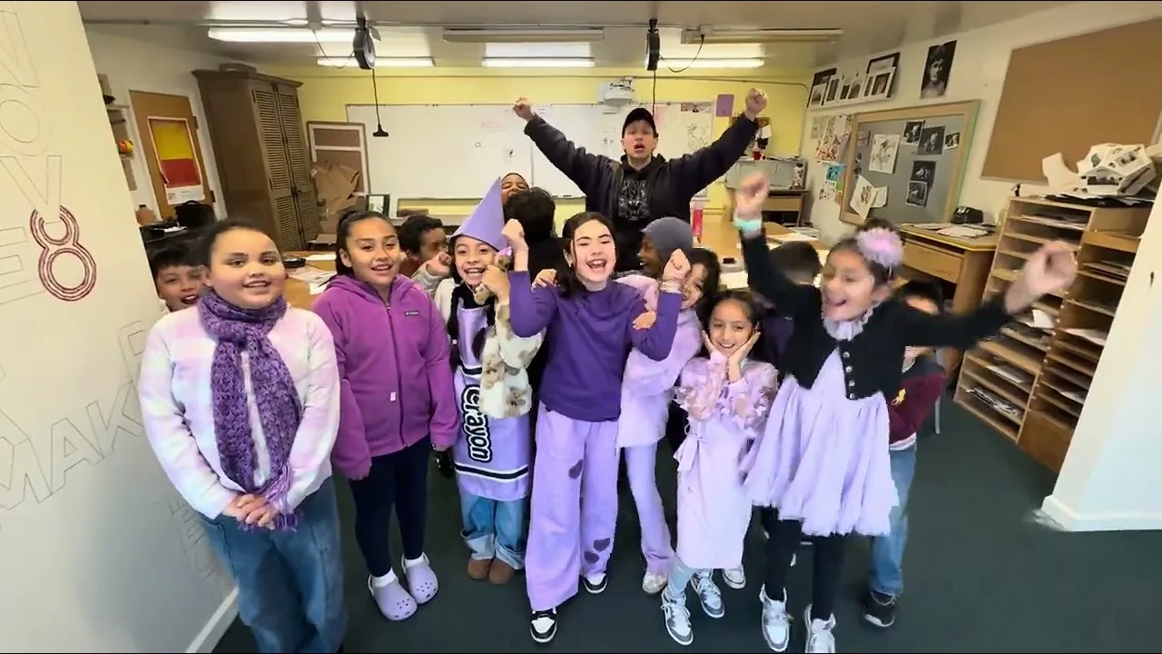 Elementary students dressed head to toe in purple, cheering together in their classroom