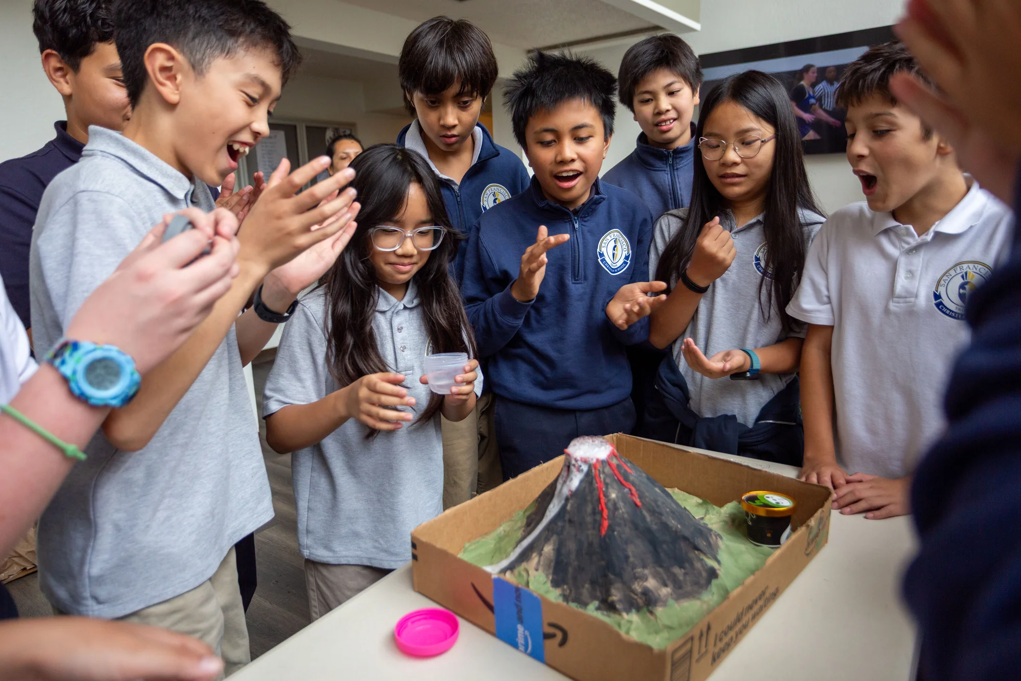 Sixth graders clapping and cheering as their model volcano erupts