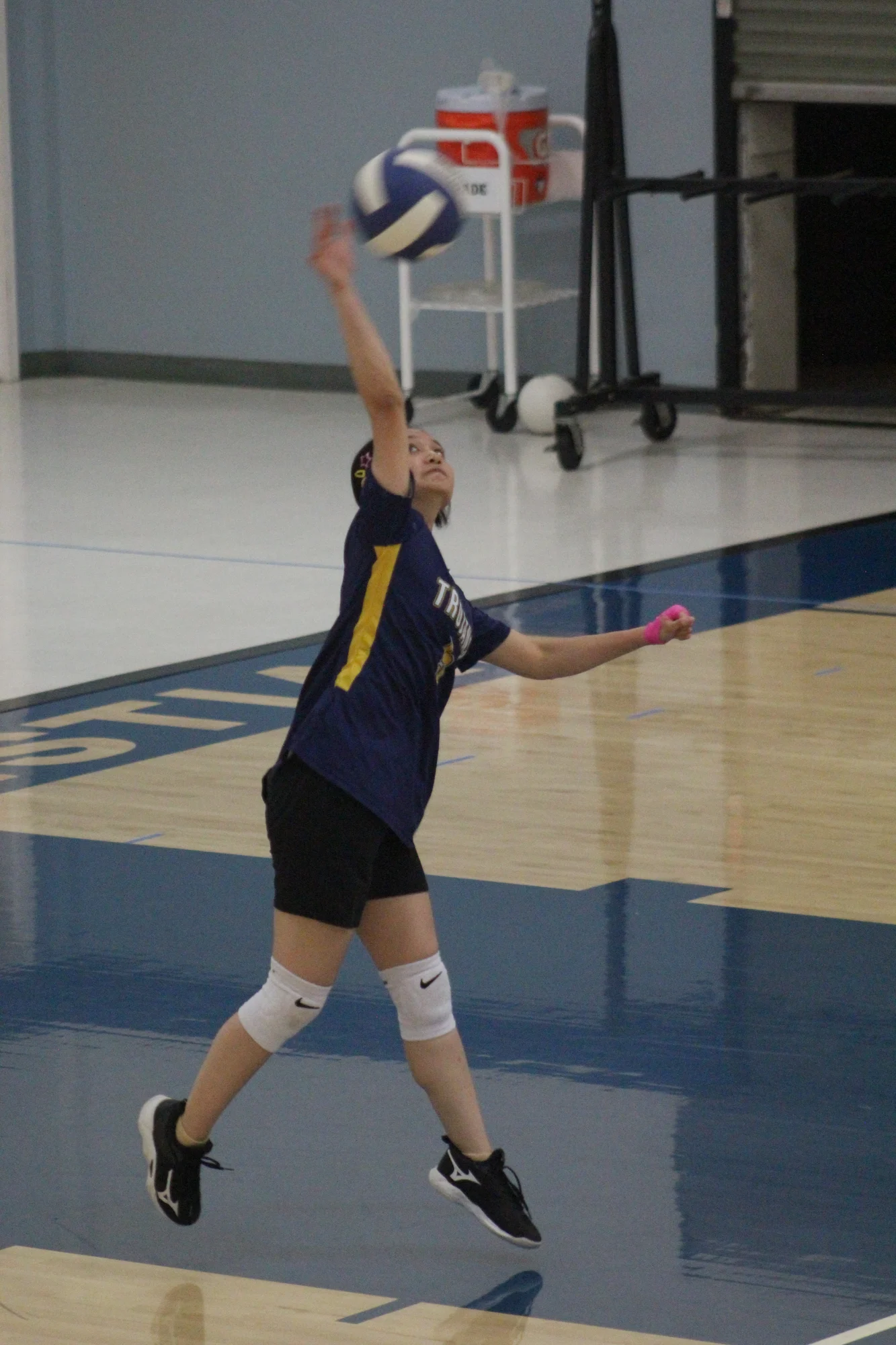 A Trojans volleyball player leaping into a jump serve