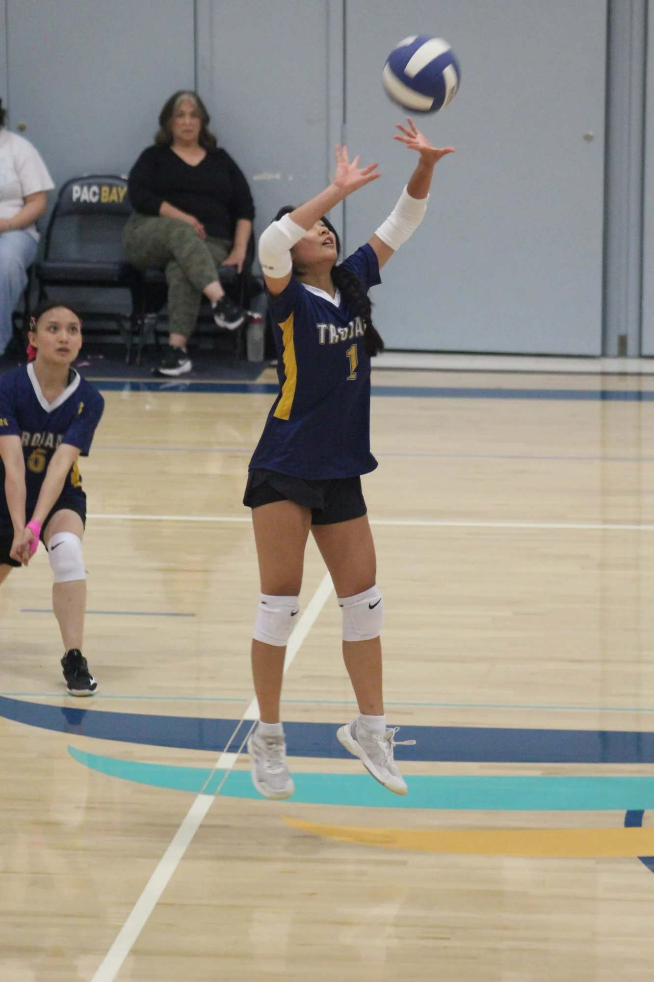 A Trojans volleyball player jumping to set the ball overhead