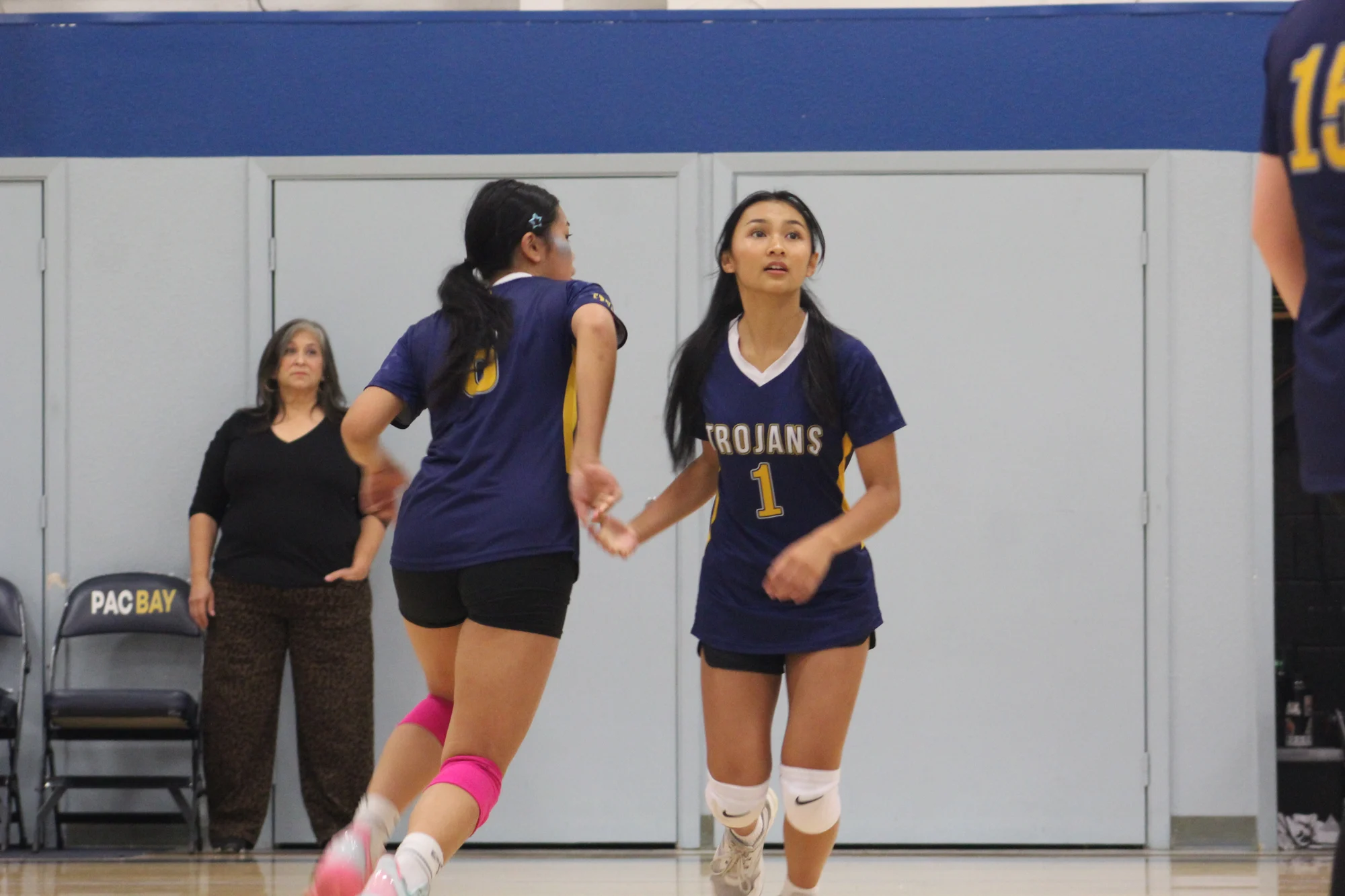 Two Trojans volleyball teammates communicating on the court