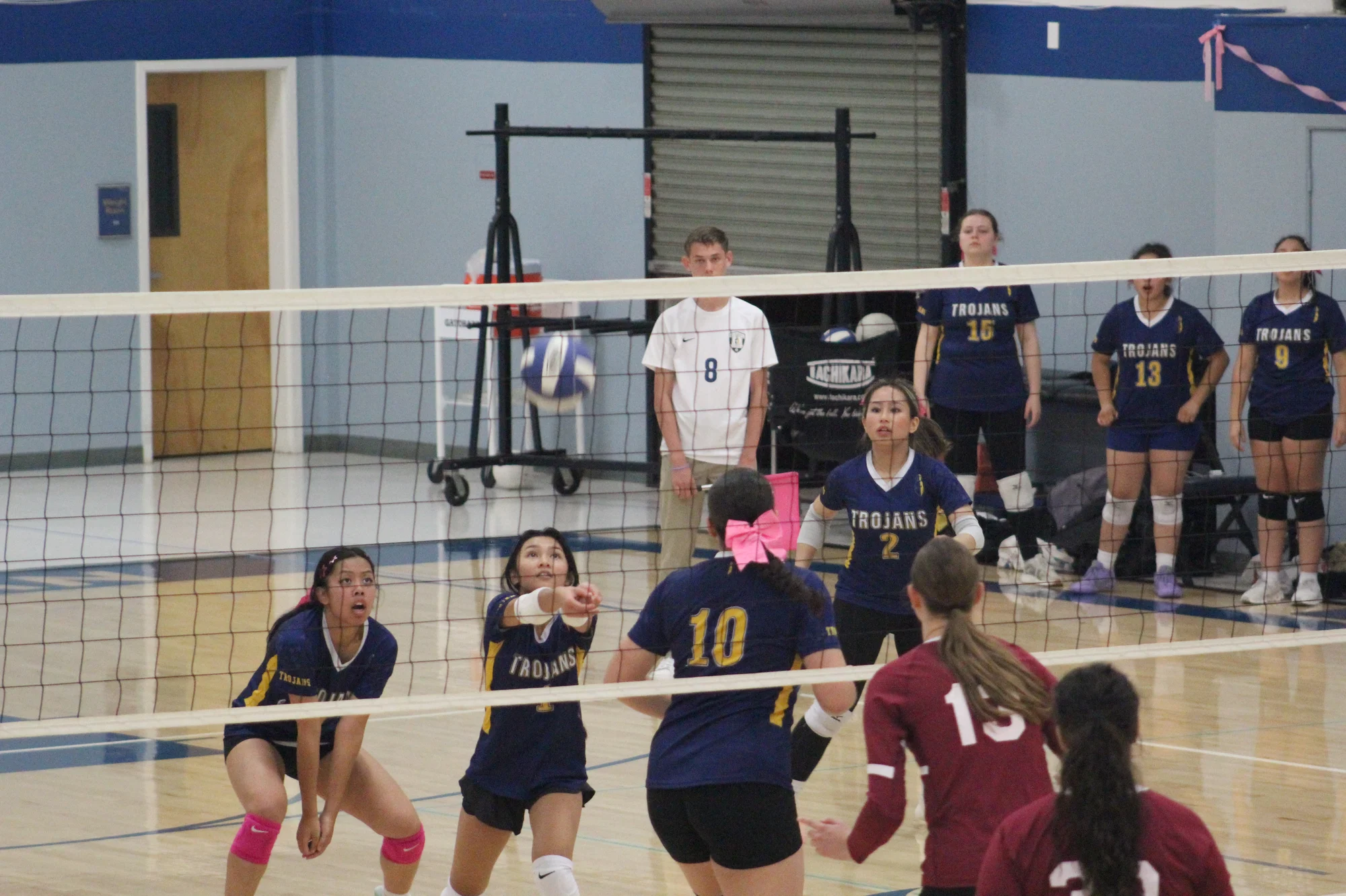 Trojans volleyball players set and ready as the ball comes over the net