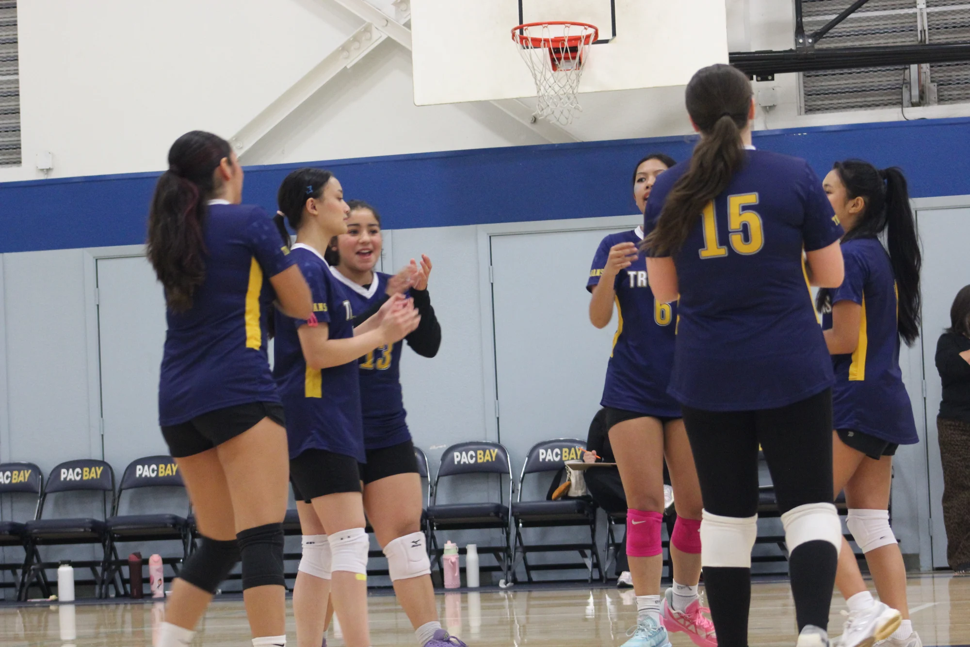 Trojans volleyball teammates gathering and applauding on the court