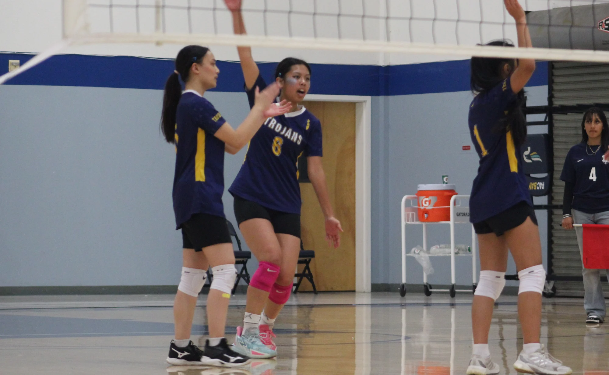 Trojans volleyball teammates encouraging one another near the net